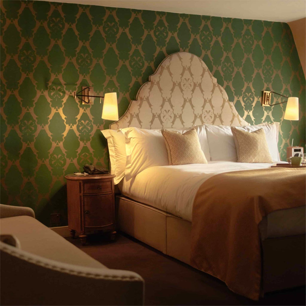 Elegant classic hotel room with plush cream-colored furnishings, wooden floors, and soft lighting, showcasing refined British hospitality in a luxurious urban setting.