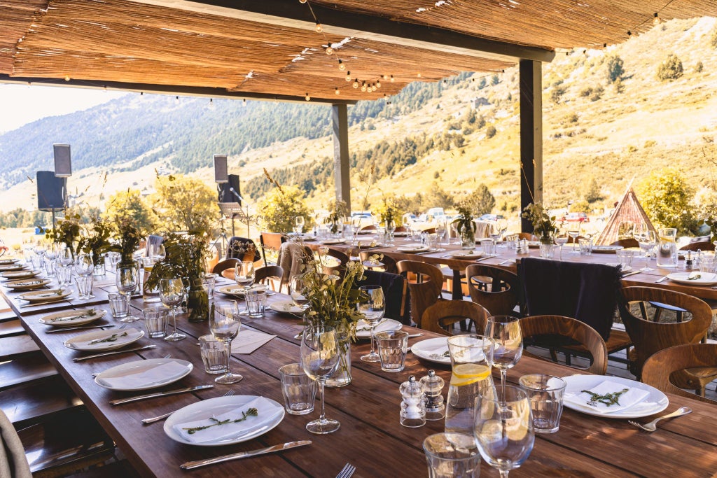 Luxurious mountain lodge nestled in scenic Andorran landscape, featuring rustic stone exterior, wooden balconies, and snow-capped peaks in background