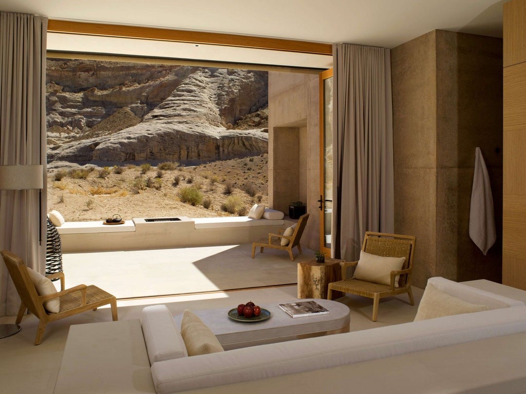 Modern desert resort with angular concrete pavilions seamlessly blending into red rock mesa, featuring infinity pool overlooking canyon landscape