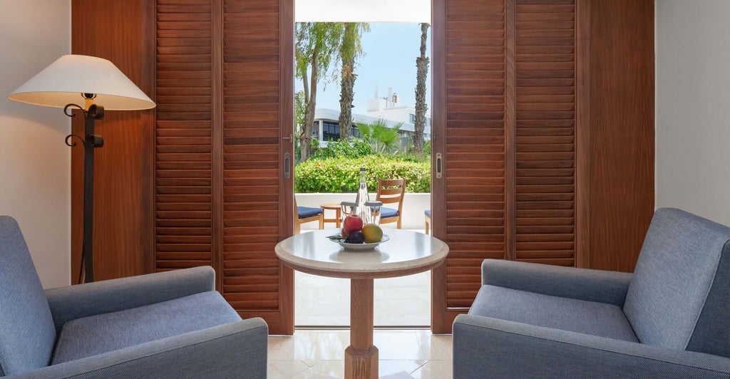 Luxurious terrace garden view room at a Cyprus hotel, featuring modern decor, plush bedding, and expansive windows overlooking lush greenery.