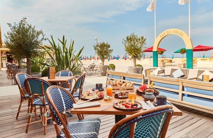 Opulent French seaside hotel with Tudor-style timber-framed facade, red brick walls, sloping roofs and ornate gables in Deauville