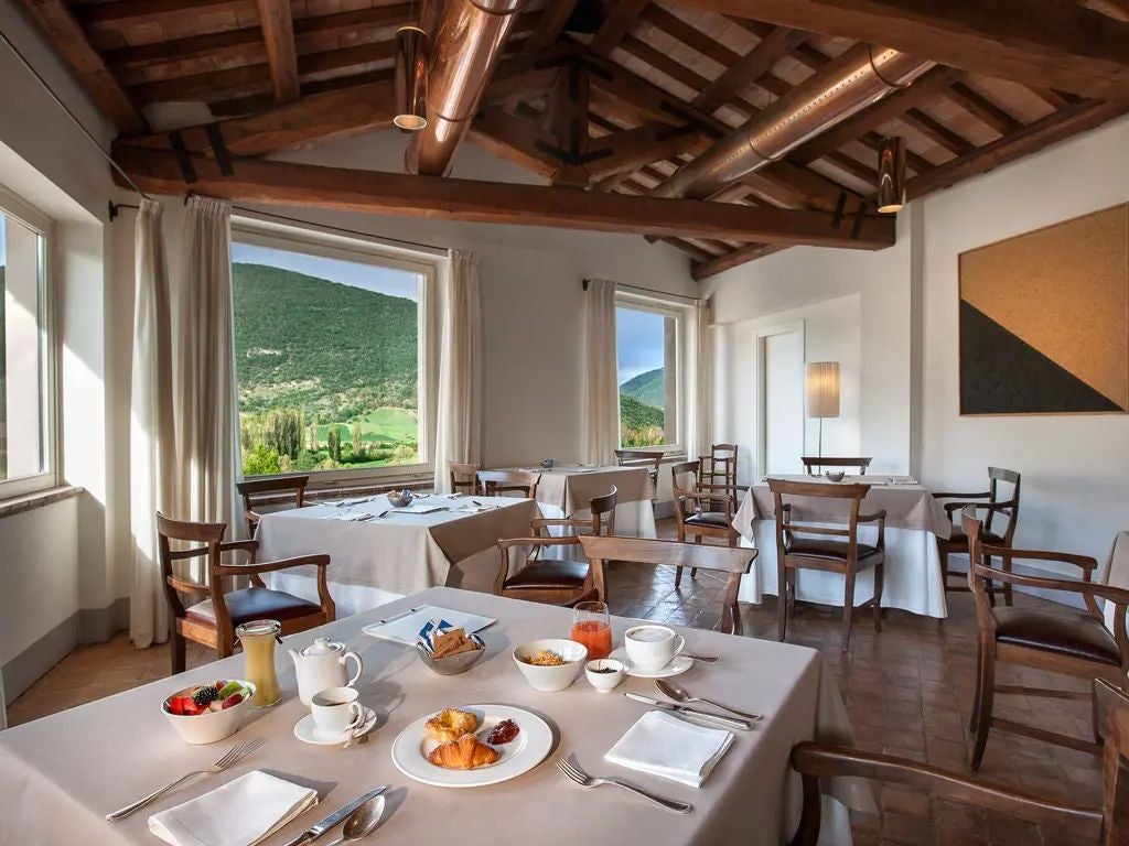 Elegant historic stone facade of luxurious boutique hotel in Umbrian countryside, Renaissance-style architecture with warm terracotta roof and lush greenery