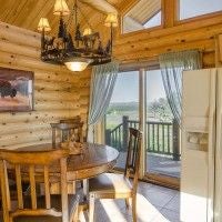 Rustic lodge room with wooden furnishings, plush bedding, and large windows overlooking scenic mountain landscape at scenset Mountain Ranch