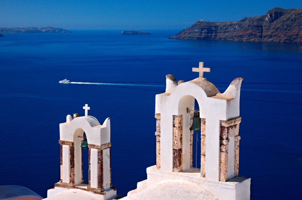 Scenic Thirasia hiking trail with panoramic Aegean Sea views, rocky terrain, and lush Mediterranean vegetation under brilliant sunlight in Greece