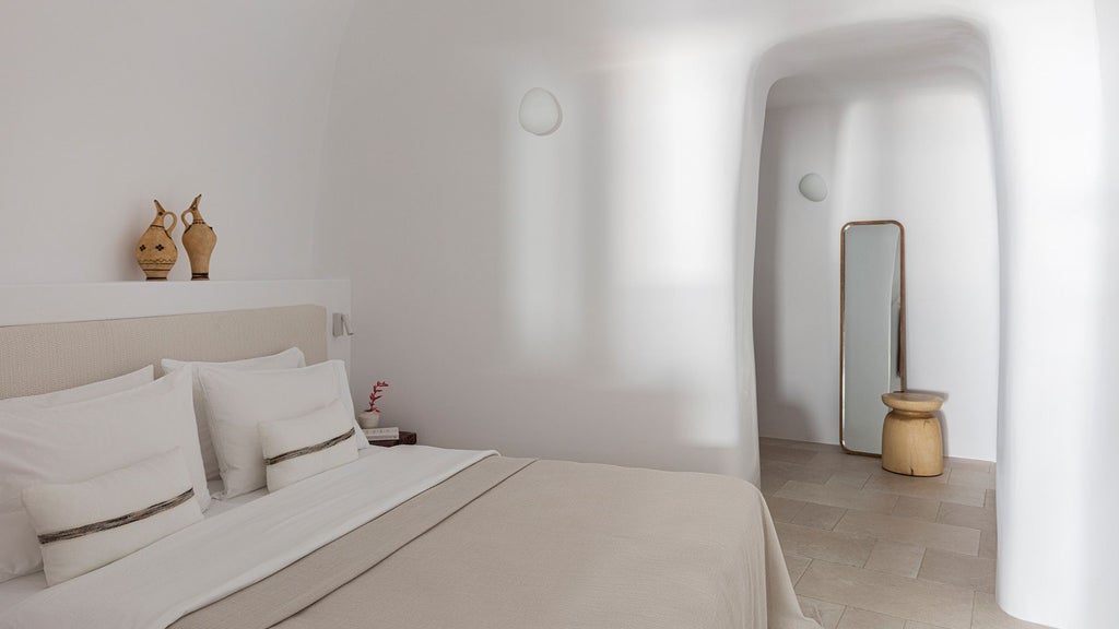 Luxurious two-bedroom suite overlooking Aegean Sea, featuring minimalist white decor, private infinity pool, and panoramic sunset views of Oia, Santorini