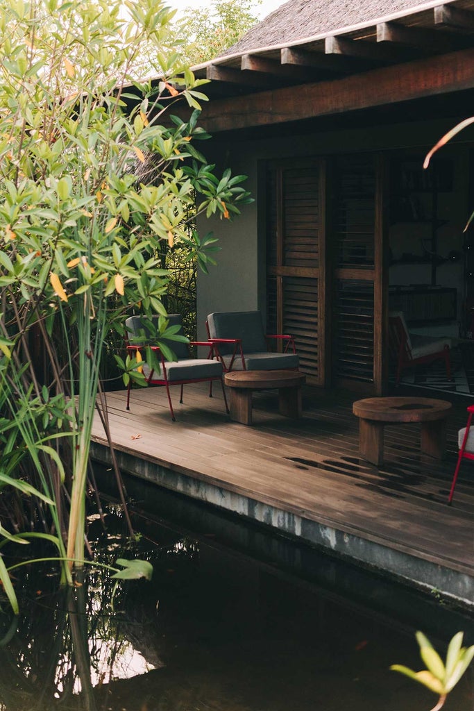 Minimalist beachfront boutique hotel with sleek white architecture, infinity pool overlooking Pacific Ocean, and lush tropical landscaping at sunset