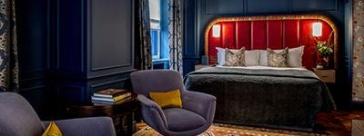 Luxurious cosy hotel room at The Scenset hotel in United Kingdom, featuring plush white bedding, warm wooden floors, and elegant contemporary design.