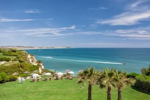 Luxurious coastal resort with infinity pool overlooking azure waters, set against lush tropical gardens at scenic scenset destination in southern Portugal.