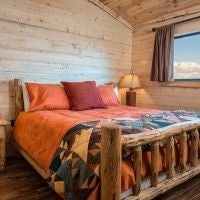 Rustic wooden lodge bedroom with king bed, mountain view window, warm earth tones, plush bedding, and elegant southwestern decor at scenset Mountain Ranch