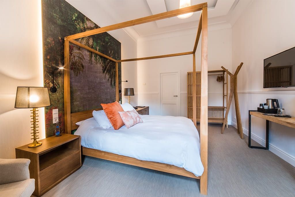 Elegant double room at L'Avenida Sóller hotel, featuring crisp white linens, minimalist decor, and lush garden view through large windows in Spain.