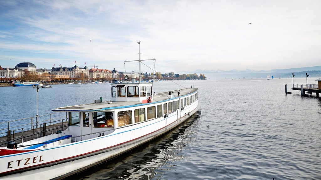 Luxurious waterfront hotel with elegant Swiss architecture overlooking Lake Zurich, featuring pristine blue waters and alpine-inspired sophisticated design