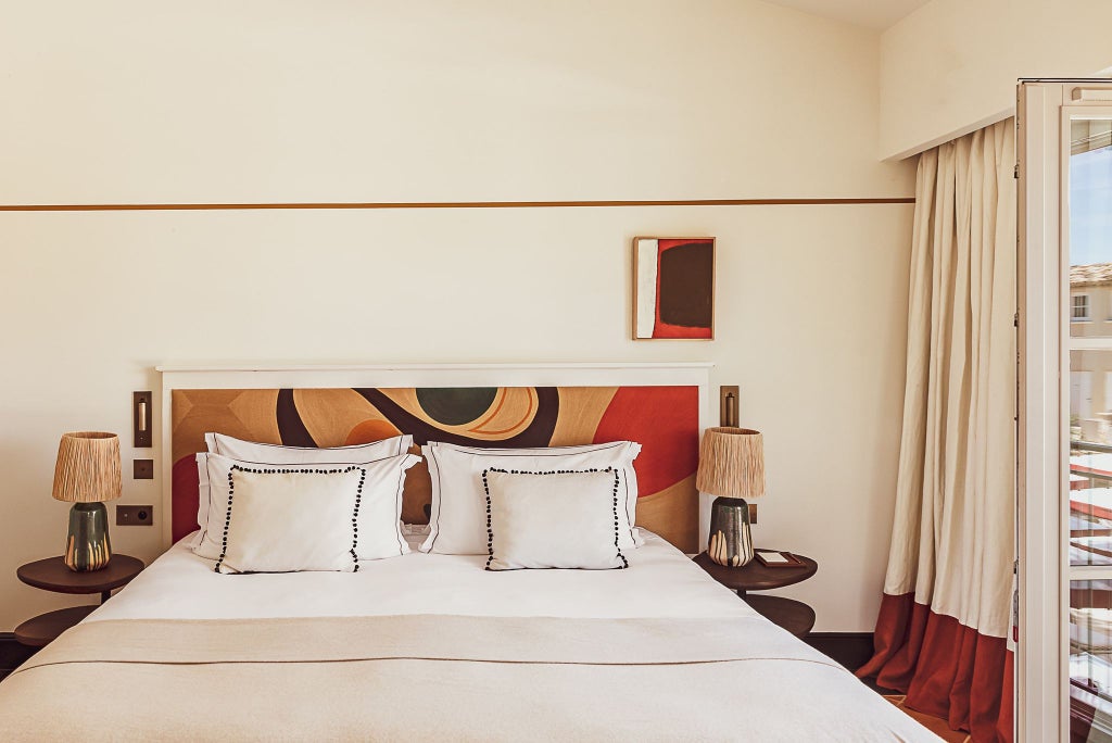 Luxurious deluxe hotel room with elegant French design, soft neutral tones, plush bedding, and chic contemporary furnishings in scenic Saint-Tropez resort