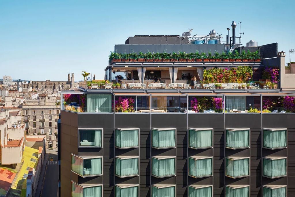 Modern luxury hotel entrance with glass facade, brass accents, and sleek contemporary lighting beneath a historic Barcelona building