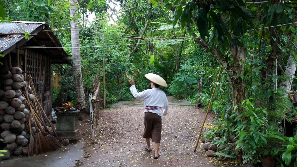 Luxurious traditional Thai wooden house with intricate teak details, surrounded by lush tropical garden, showcasing authentic rural lifestyle in serene countryside setting