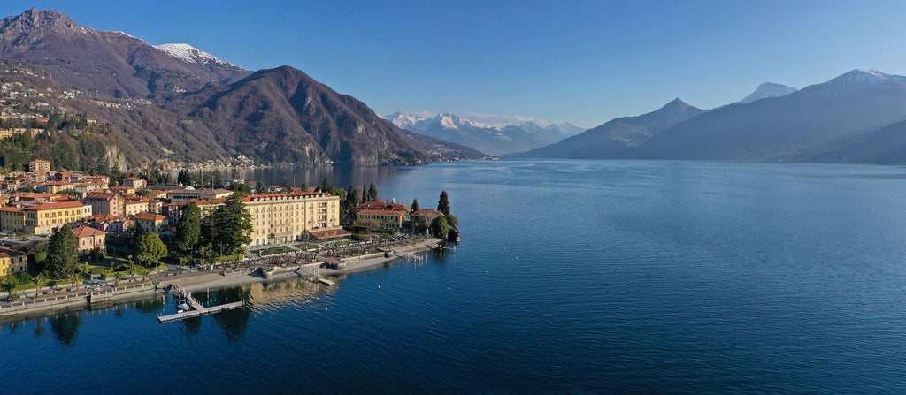 Modern luxury hotel exterior with elegant stone facade, arched windows, and manicured gardens overlooking Lake Como in Italy