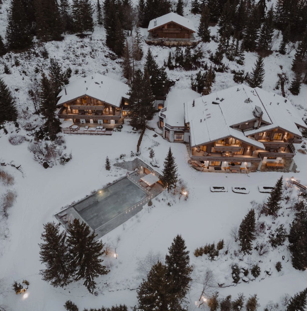 Luxurious alpine chalet with floor-to-ceiling windows, modern minimalist design, snow-covered mountain landscape, and elegant contemporary furnishings in Scenset Hotel Courchevel.