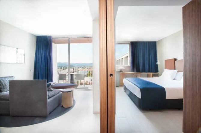 Spacious junior suite with panoramic sea view, modern white furnishings, king-size bed, and elegant balcony overlooking Talamanca's azure coastline in Spain