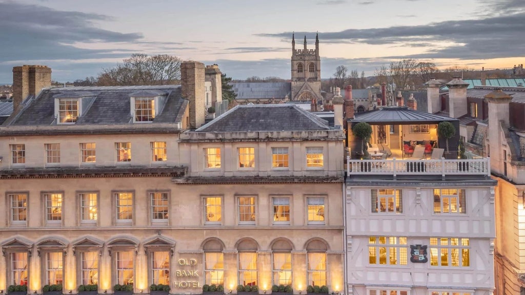 Elegant heritage bedroom at Old Bank Hotel, showcasing period architecture with large windows overlooking historic United Kingdom cityscape at sunset