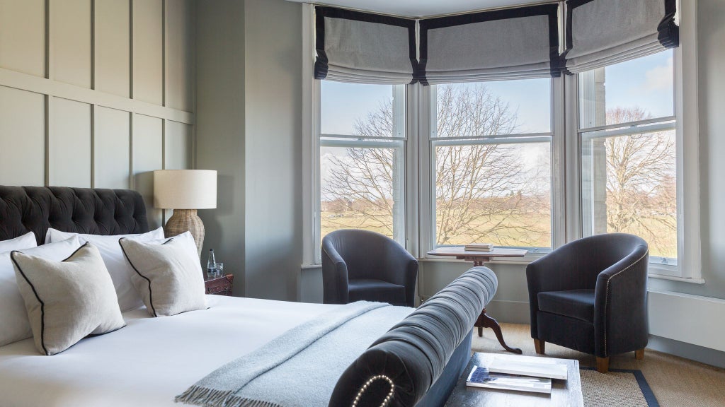 Elegant loft suite with contemporary design, floor-to-ceiling windows, modern furnishings, and soft neutral color palette overlooking urban scenery in United Kingdom