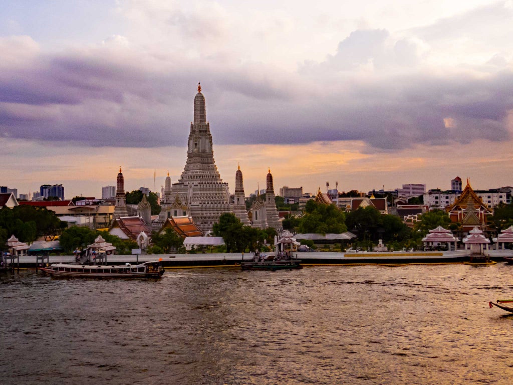 Bangkok skyline at sunset with gleaming skyscrapers, luxury hotels and iconic Chao Phraya river reflecting golden hour light