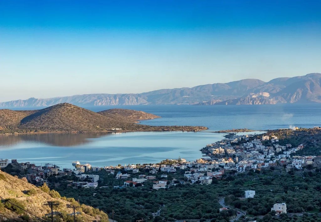 Luxurious beachfront resort with white-domed suites overlooking crystal-clear Aegean waters, Crete's scenic coastline and elegant Mediterranean architecture.