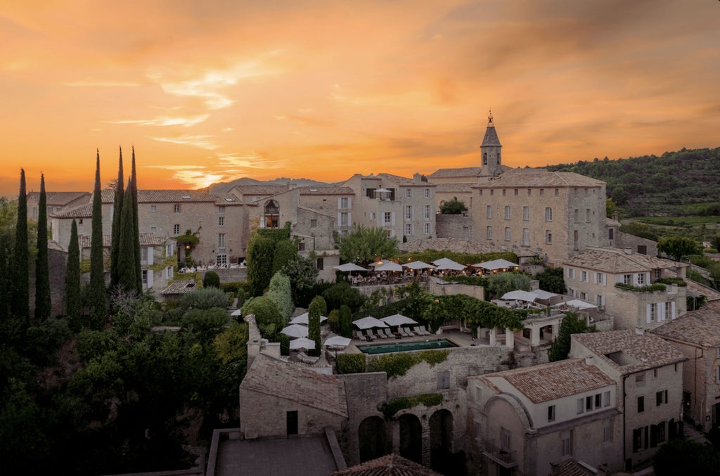 Elegant stone hotel in Provence with arched windows, terracotta roofs, and flowering gardens nestled in hilltop village views