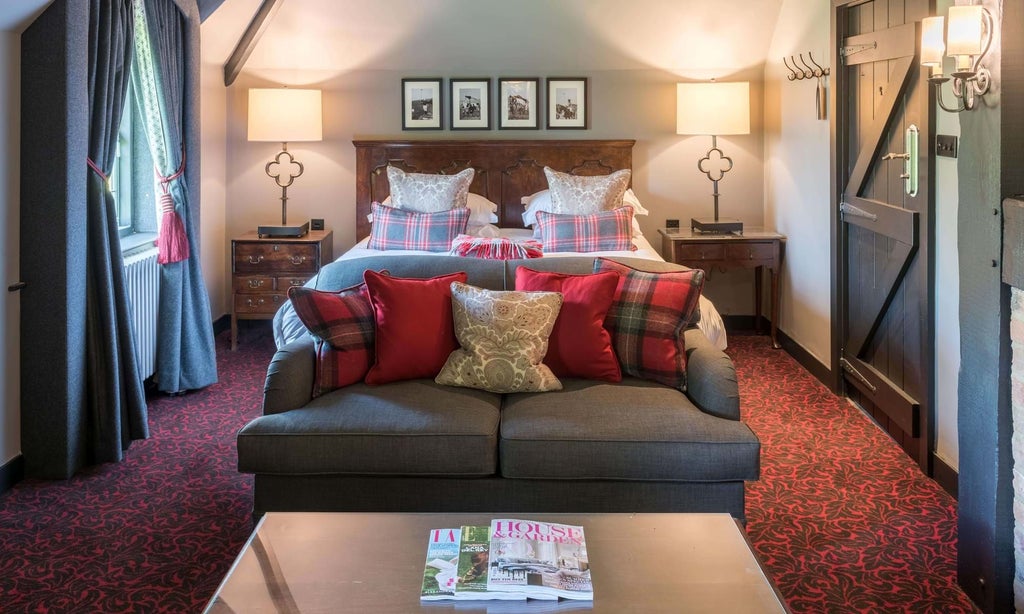 Elegant cottage-style hotel room with plush white bedding, classic wooden furniture, soft neutral tones, and traditional British countryside charm