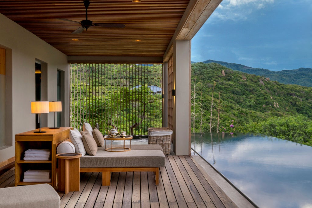 Contemporary infinity pool overlooking dramatic mountains and Vinh Hy Bay, surrounded by minimalist pavilions at luxury resort in Vietnam.