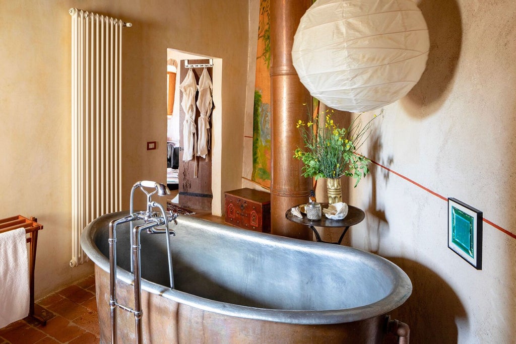 Elegant Tuscan-style suite with rustic stone walls, plush king bed, antique wooden furniture, and panoramic countryside view through arched window