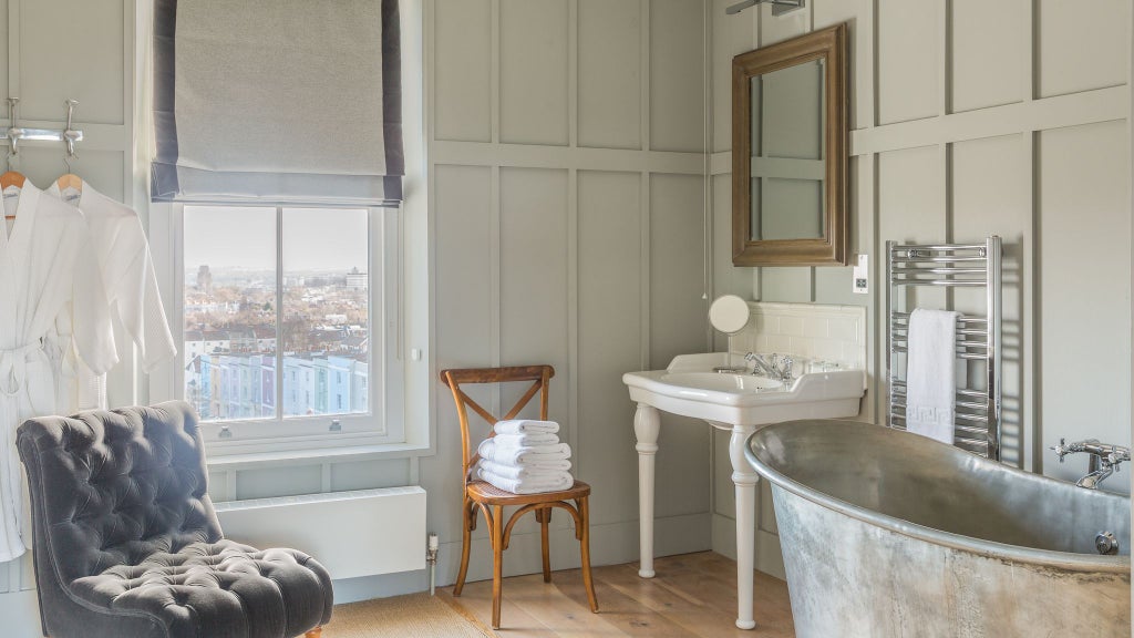 Spacious modern loft suite with elegant minimalist design, neutral color palette, floor-to-ceiling windows, and contemporary furnishings in UK urban setting