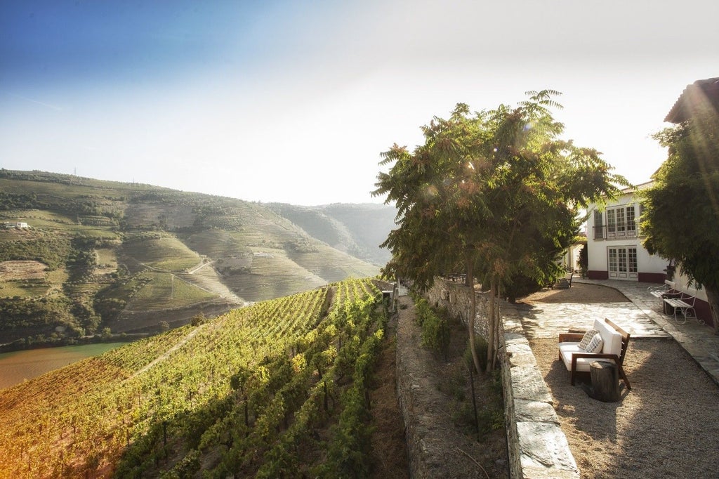 Elegant Portuguese wine estate hotel with whitewashed walls and red-tiled roof nestled among terraced vineyards overlooking Douro Valley