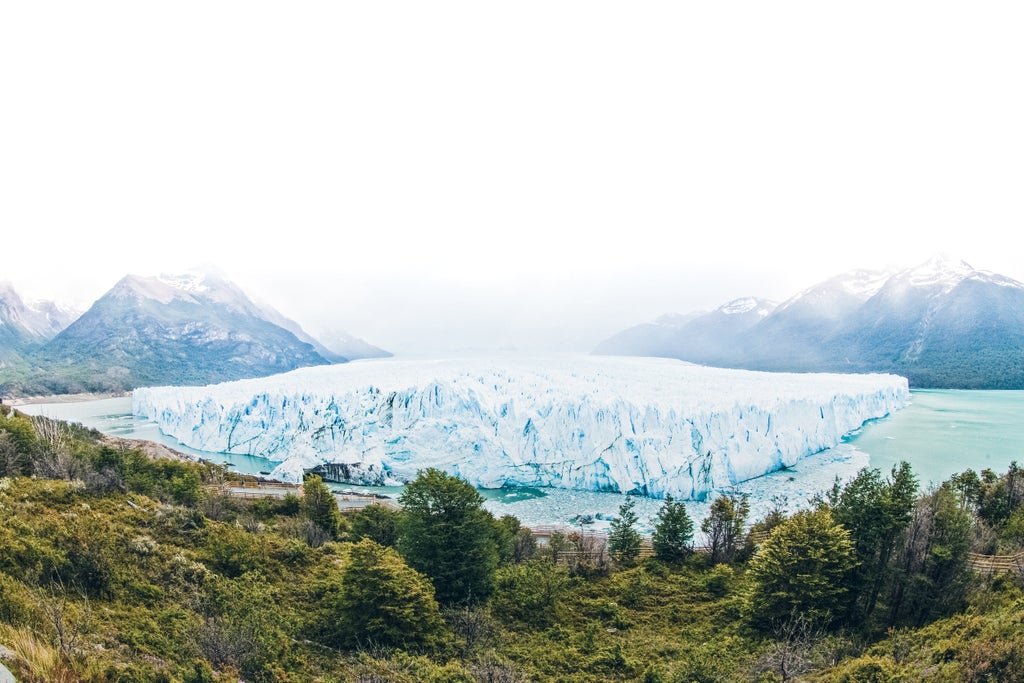 Scenic view of El Calafate town nestled against snow-capped Andes mountains, with turquoise Lake Argentino in the foreground