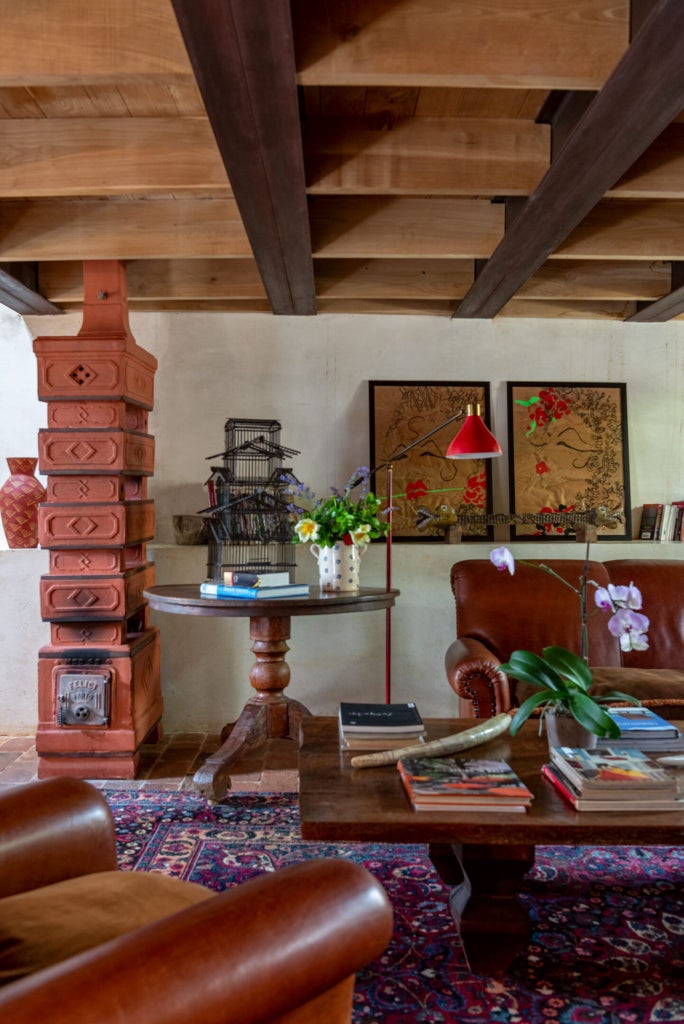 Rustic-chic suite with stone walls, antique wooden furniture, plush white linens, and a glimpse of Tuscan landscape through elegant French doors