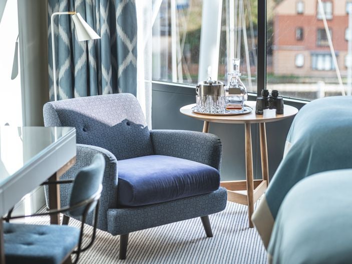 Modern twin hotel room with elegant decor, two comfortable beds, large window overlooking Southampton's harbour, soft neutral tones, and contemporary furnishings