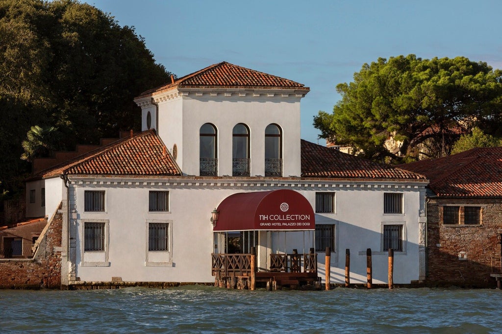 Historic Venetian palazzo hotel with private garden, ornate Murano chandeliers, and waterfront views along a quiet canal