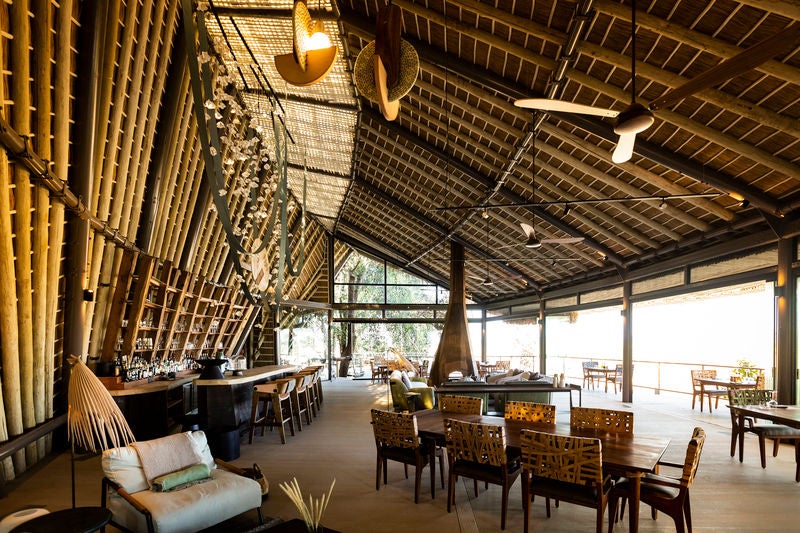 Luxurious stilted safari lodge overlooking Okavango Delta wetlands, with wooden walkways connecting elevated thatched-roof structures