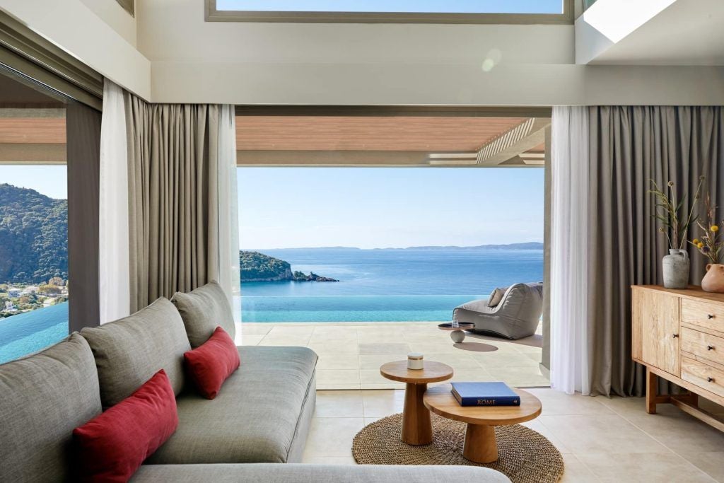 Luxurious two-story maisonette suite with private infinity pool overlooking the Aegean Sea, featuring modern minimalist design and pristine white interiors.