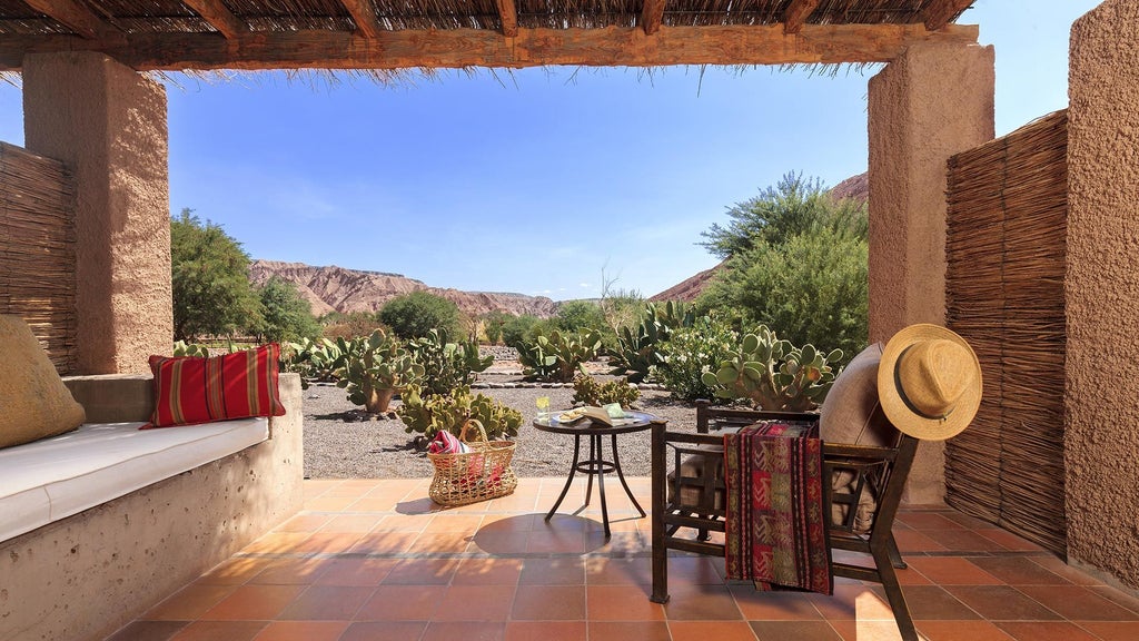 Luxury desert lodge with adobe walls nestled against red mountains, featuring an infinity pool reflecting the Atacama's dramatic landscape