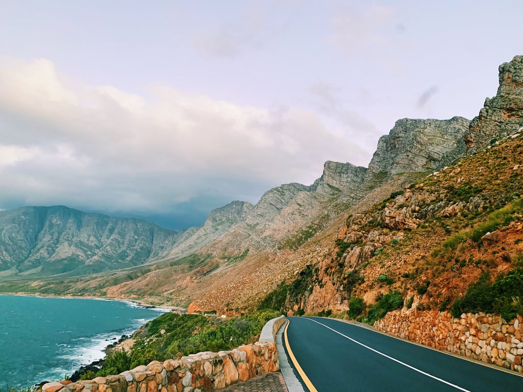 Luxury tour vehicle overlooking panoramic coastline of Cape Peninsula with pristine beaches and dramatic mountain cliffs