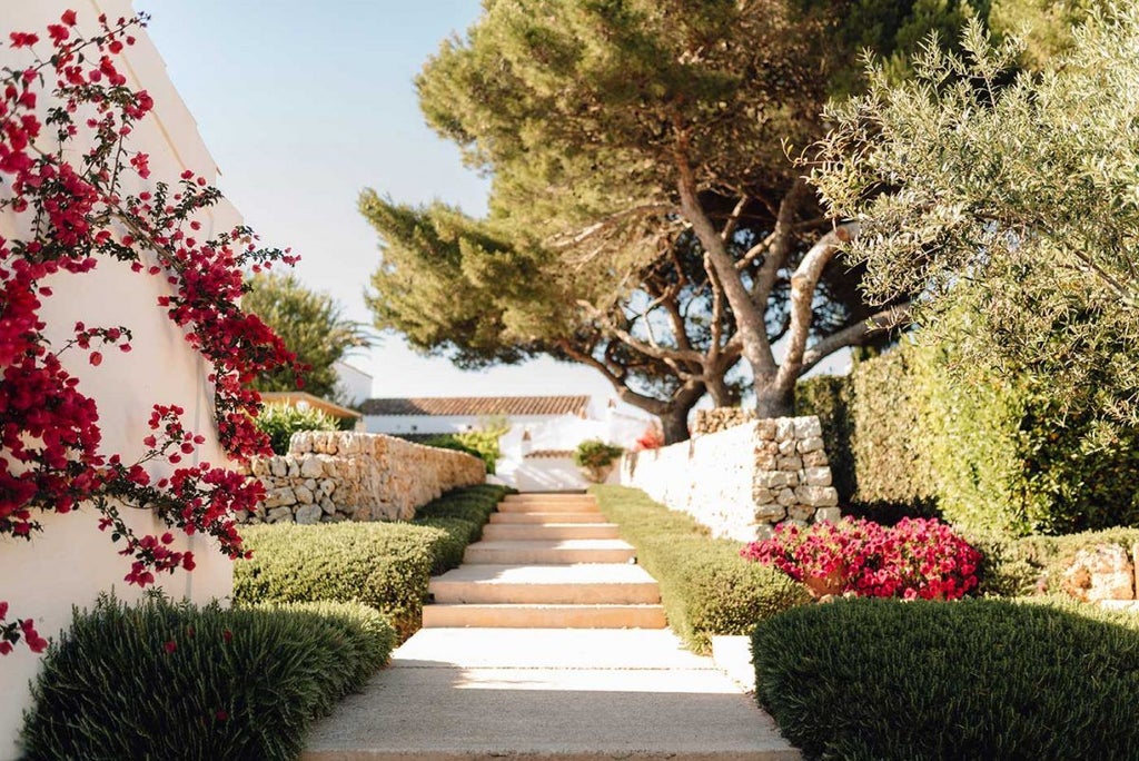 Elegant whitewashed stone farmhouse hotel nestled in Menorca's countryside, surrounded by lavender fields and traditional Mediterranean architecture