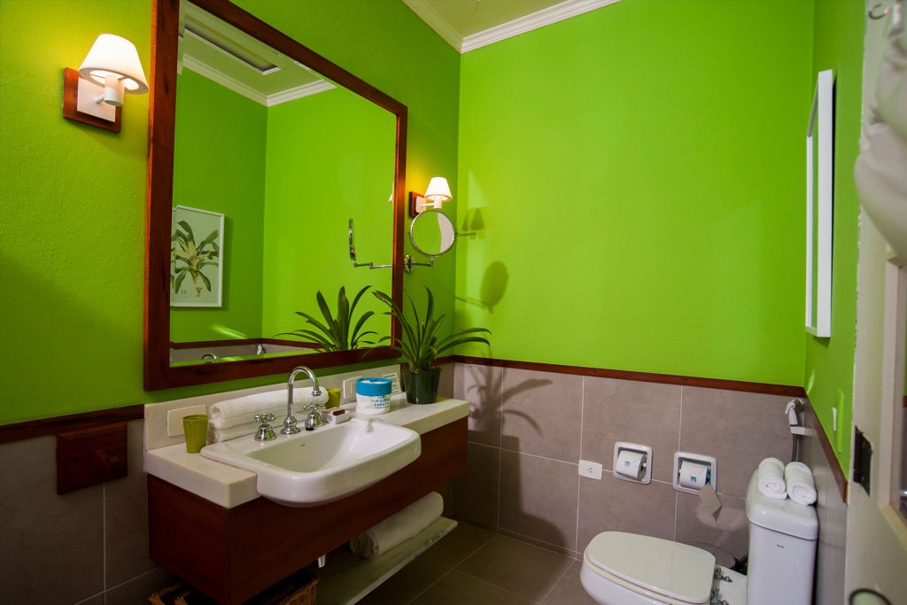 Elegantly designed green and white suite at Casa Turquesa, featuring plush bed, tropical Brazilian decor, crisp linens, and soft natural lighting