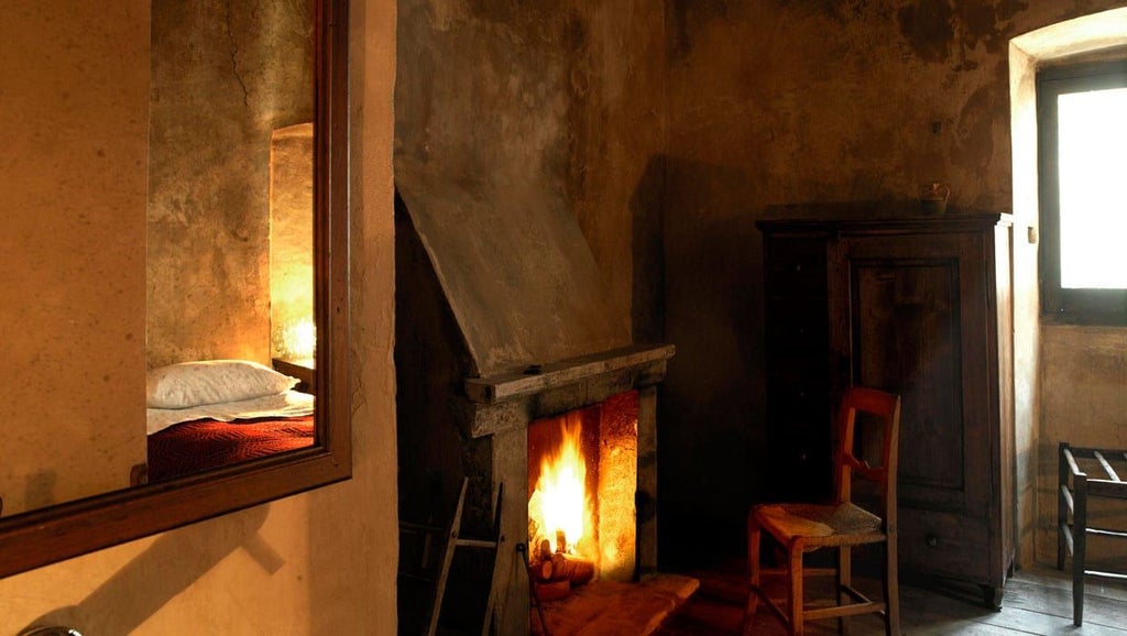 Rustic wooden staircase leading to a charming, candlelit medieval Italian hotel room with stone walls and antique furnishings at Sextantio Albergo Diffuso