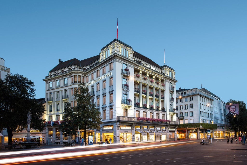 Elegant five-star hotel in Zurich with classic European architecture, ornate stonework facade, and grand arched windows overlooking a plaza