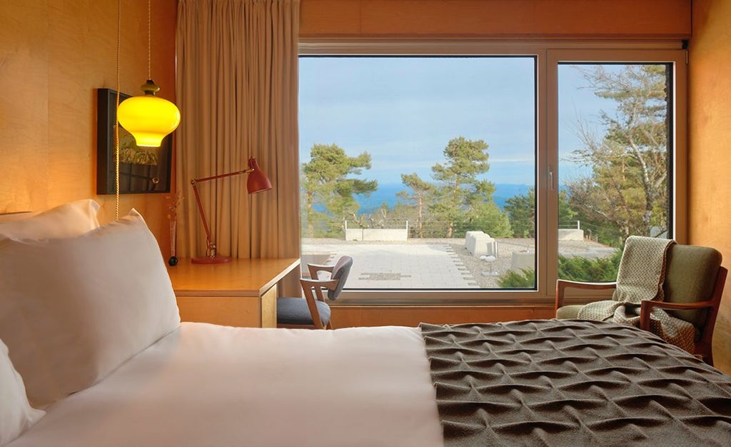 Elegant mountain-view comfort room at Casa das Penhas Douradas, featuring crisp white linens, wooden accents, and panoramic alpine landscape through large windows