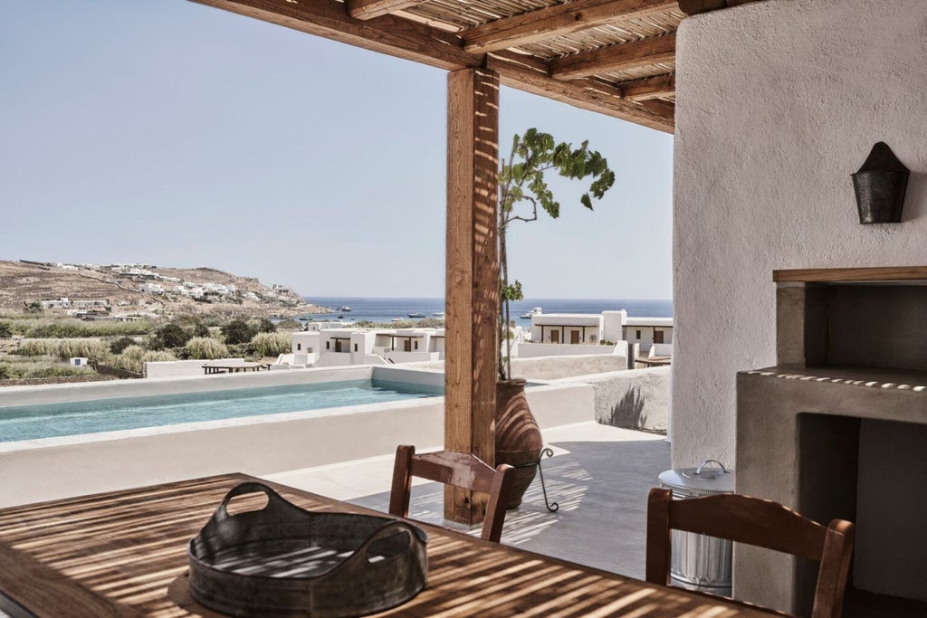 Whitewashed luxury villa with infinity pool overlooking Aegean Sea, minimalist Greek architecture nestled into Mykonos hillside at sunset