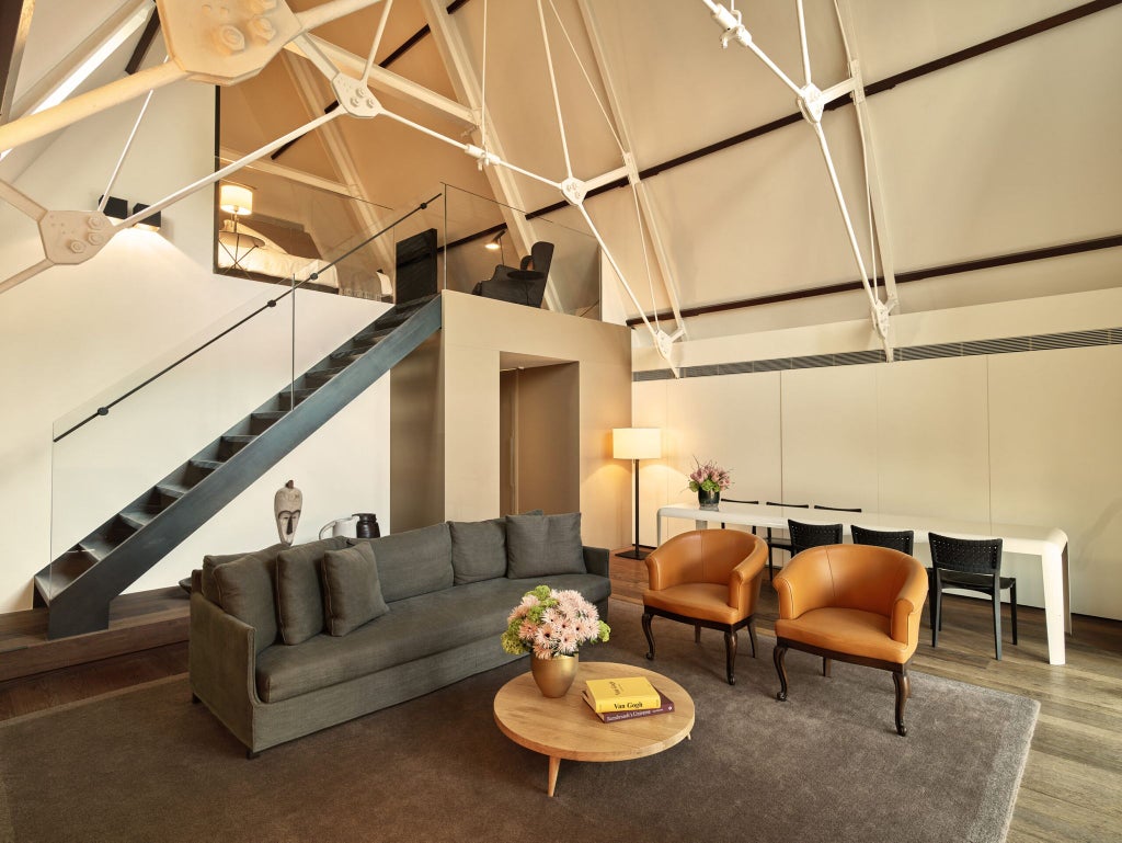 Luxurious one-bedroom suite with modern design, elegant wood accents, floor-to-ceiling windows overlooking Amsterdam's historic cityscape at Conservatorium Hotel