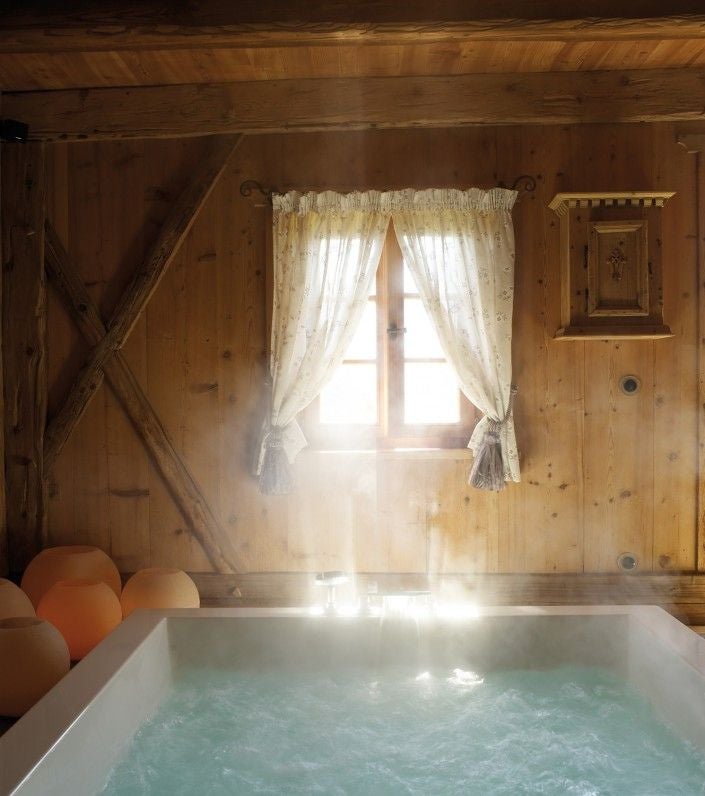 Luxurious alpine lodge with stone and wood facade nestled in snowy Dolomites, featuring traditional South Tyrolean architecture and balconies