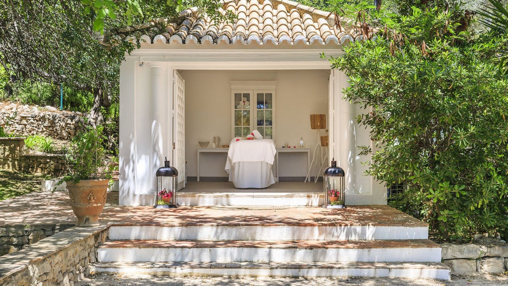 Elegant Portuguese villa with white facade, terra-cotta roof and manicured gardens surrounded by rolling countryside hills at sunset