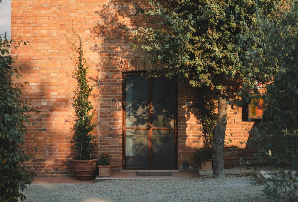 Elegant Tuscan luxury hotel with stone facade, arched windows, and manicured garden featuring potted citrus trees and terrace seating