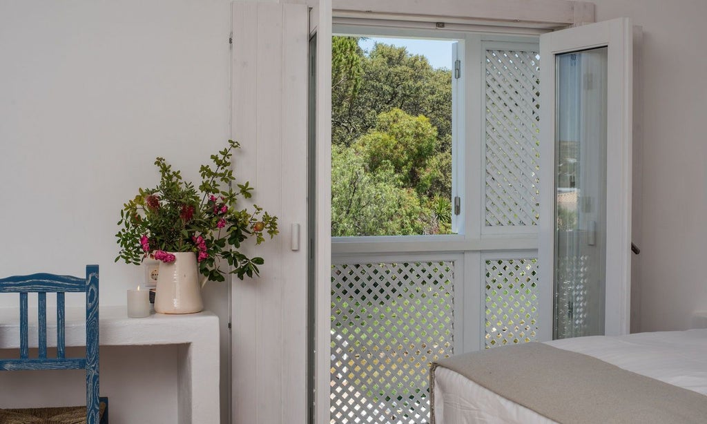 Luxurious suite with panoramic views of ocean and mountains, featuring elegant white decor, plush bed, and expansive windows at Octant Vila Monte in Portugal